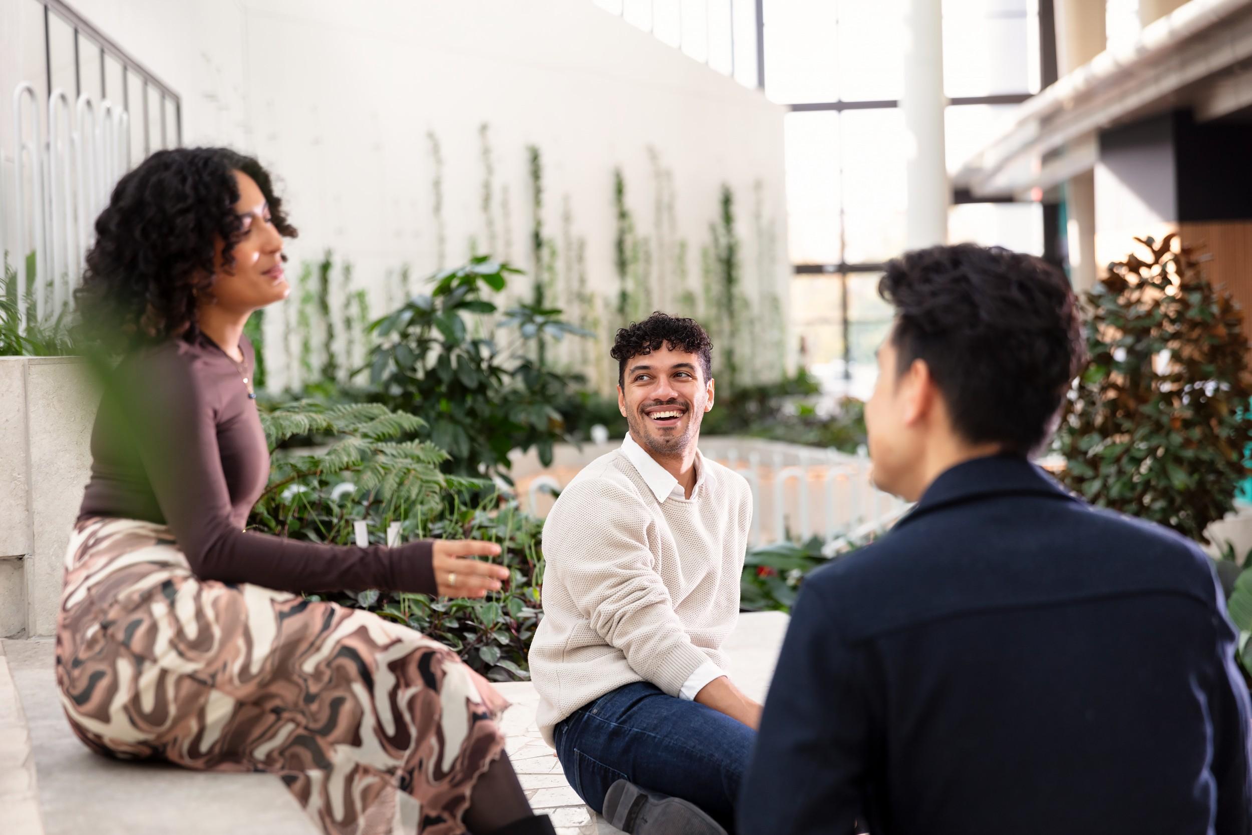 Three people talking and smiling in an airy garden setting